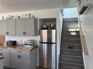 Eine Küche mit weißen Schränken, einem Edelstahl-Kühlschrank, einem Toaster und einer Holzausziehtafel.