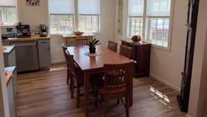 A kitchen with a wooden table, chairs, a coffee maker, and a clock on the wall. - Spacious 2-bedroom house in Stone Ridge with outdoor patio with beautiful view. (Stone Ridge)