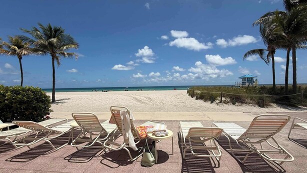 A beachside lounge area with sun loungers, a small table, and a view of the beach and ocean. - Oceanfront Escape on Hollywood Beach (Hollywood)