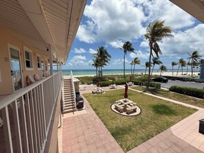 Ein Hotelbalkon mit Blick auf den Strand, Palmen und einen Parkplatz.