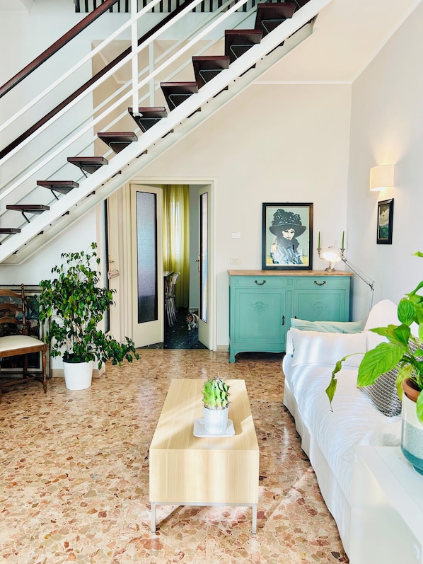 A living room with a staircase, a dining area, a teal cabinet, and a white sofa. - CasaMilla-Viareggio-villetta-mare-relax-6 places (Viareggio)