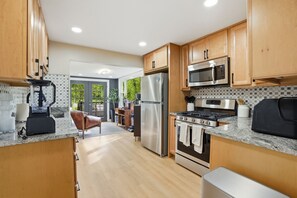 Une cuisine moderne avec des meubles en bois, des appareils électroménagers en acier inoxydable et un plan de travail en granit.