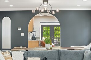Un salon moderne avec un canapé gris, une table basse et une cuisine visible à travers une arche.