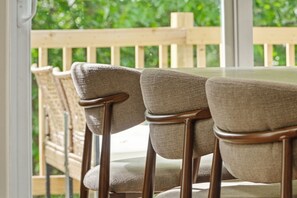 A row of chairs with wooden frames and fabric seats, positioned on a balcony with a wooden railing and greenery in the background. - Three Waters Escape | 2 Kings | Game Lounge (Valparaiso)