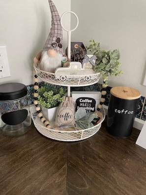 A three-tiered coffee-themed decorative stand with a gnome figure, coffee-themed signs, and a small plant.