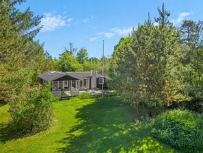 A house with a deck, surrounded by lush greenery and trees.