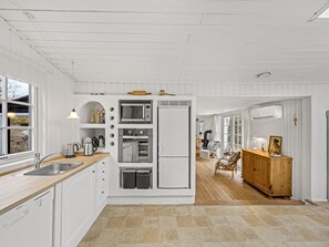 A modern kitchen with white cabinetry, a built-in oven, and a refrigerator.