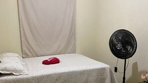 A bedroom with a bed, a bedside table, a fan, a rug, and a curtain. - Your perfect family retreat (Divinópolis)
