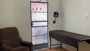 A room with a brown armchair, a fur rug, a metal table, and a door with a metal gate. - Your perfect family retreat (Divinópolis)