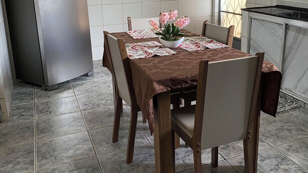 A kitchen with a dining table, chairs, a refrigerator, and a window with decorative bars. - Your perfect family retreat (Divinópolis)