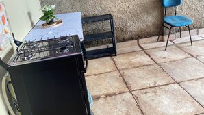 A kitchen with a gas stove, a blue chair, and a small table with a plant. - Your perfect family retreat (Divinópolis)