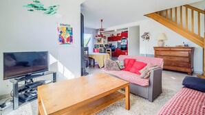 Een woonkamer met een televisie, bank en houten tafel.