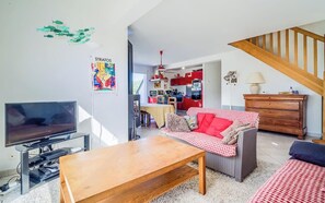 Ein Wohnzimmer mit Fernseher, Sofa und Holztisch.