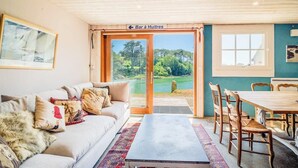 Une pièce comprenant un canapé, une table et des chaises, avec vue sur l’extérieur, et une enseigne indiquant la présence d’un bar.