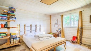 Une pièce en bois avec un lit, une table de chevet, une bibliothèque et une fenêtre.