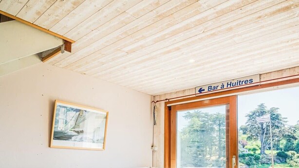 Un salon chaleureux avec un canapé, une table basse et un tapis. Une fenêtre offre une vue sur un lac et des arbres.
