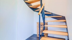 Moderni, spiraalimainen portaikko, jossa on puiset askelmat ja metallikaiteet.