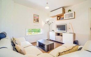 Ein modernes Wohnzimmer mit einer Couch, Couchtisch, Fernseher und Regalen.