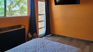A bedroom with a bed, a TV mounted on the wall, a window with curtains, and a fan. - Family Weekend: Private Pool, Barbeque, Sun and Relaxation (Xochitepec)