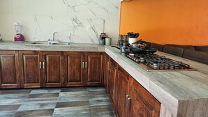 A kitchen with marble walls, wooden cabinets, a gas stove, and a checkered floor. - Family Weekend: Private Pool, Barbeque, Sun and Relaxation (Xochitepec)