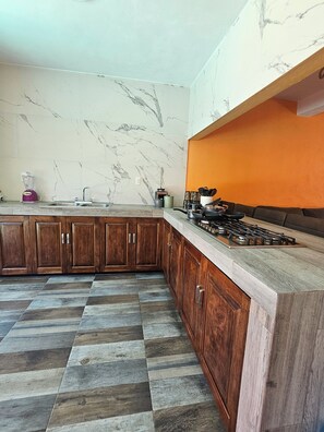 A kitchen with marble walls, wooden cabinets, a gas stove, and a checkered floor. - Family Weekend: Private Pool, Barbeque, Sun and Relaxation (Xochitepec)
