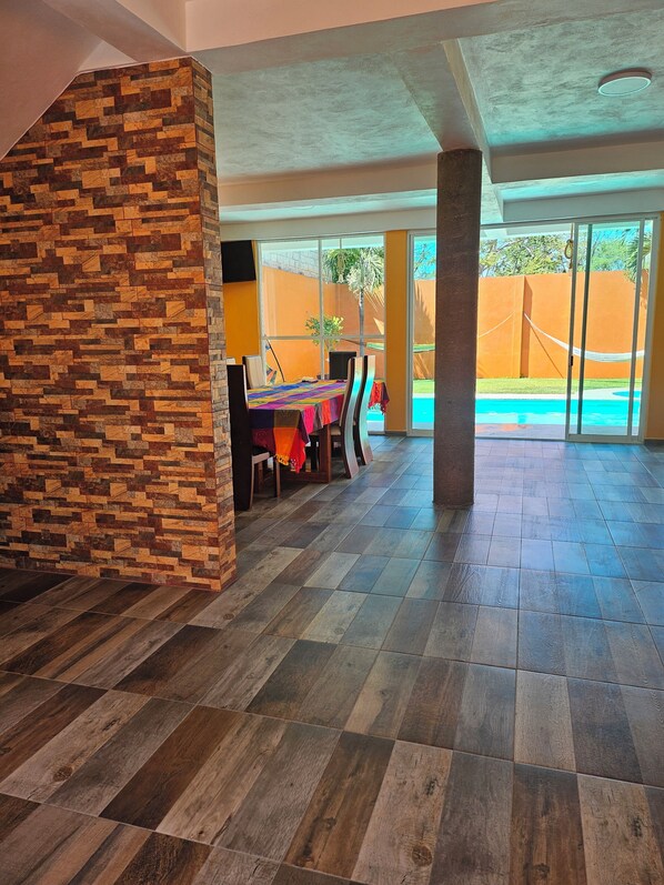 A spacious room with a tiled floor, a dining area with a table and chairs, and a view of a swimming pool. - Family Weekend: Private Pool, Barbeque, Sun and Relaxation (Xochitepec)
