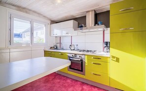 Eine Küche mit weißer Arbeitsplatte, gelben Schränken, einem eingebauten Backofen und einem Fenster mit Blick auf Häuser.