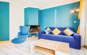 Ein Zimmer mit einem blauen Sofa, einem blauen Sessel, einem Couchtisch und einem Kamin.