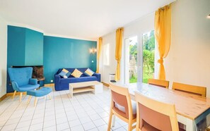 Ein Wohnzimmer mit einer Couch, Sesseln, einem Tisch und Blick durch eine Glastür.