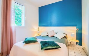 Ein Schlafzimmer mit einem großen Bett, einem Nachttisch, einer Lampe und Blick auf Grün.