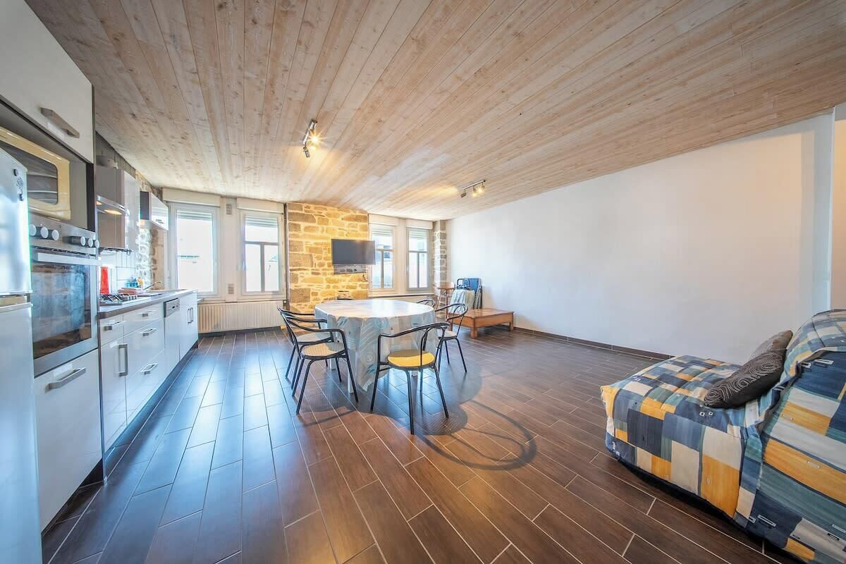 Et moderne køkken med stenvæg, træloft og spiseplads med et rundt bord og stole.