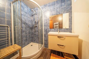 A bathroom with a glass-enclosed shower, a white sink, and a mirror above it. - Pause Vacances : Grand T3 Lumineux (Guidel)