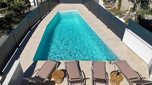 Ein rechteckiger Pool mit klarem Wasser, umgeben von einer gefliesten Liegefläche.