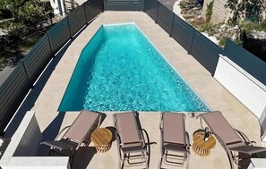 Ein rechteckiger Pool mit klarem Wasser, umgeben von einer gefliesten Liegefläche.