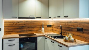 Eine moderne Küche mit weißen Schränken, einer Holzrückwand, einem Herd und einem Spülbecken.
