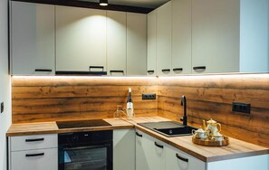 Eine moderne Küche mit weißen Schränken, einer Holzrückwand, einem Herd und einem Spülbecken.