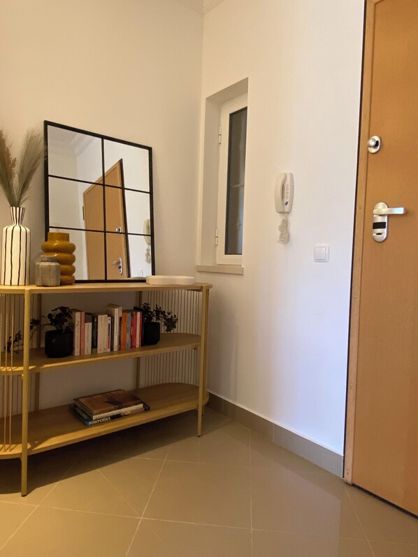 Ein Eckzimmer mit einer Holzbücherwand, einem gerahmten Kunstwerk, einer Tür mit Fenster und einem an der Wand montierten Telefon.