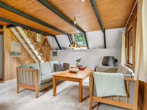 Ein Loft-Zimmer mit Holzbalkendecke, einer Couch, einem Tisch und einer Treppe.