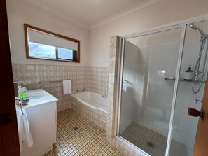 Un baño con bañera, ducha, lavamanos y ventana.