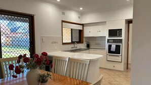 Une cuisine moderne dotée d’un îlot central, de meubles blancs et d’appareils électroménagers intégrés.
