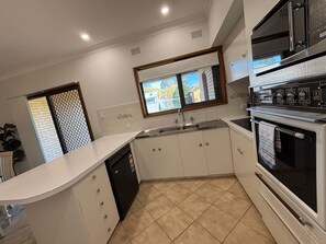 A kitchen with white cabinets, a built-in oven, a dishwasher, and a window with a view.