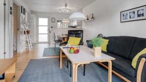 A modern living room with a sofa, a dining table, and a kitchen area in the background. - "Enwald" - 100m from the sea by Interhome (Hals)