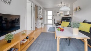 A modern living room with a flat-screen TV, wooden furniture, a dining table with fruit, and a sofa with cushions. - "Enwald" - 100m from the sea by Interhome (Hals)