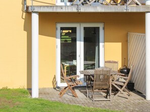 A patio with a table and chairs, a sliding glass door, and a wooden fence.