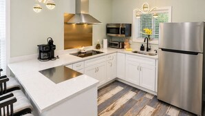 A modern kitchen with white cabinetry, stainless steel appliances, and a central island. - Lefty’s Poolside Retreat (Lewes)