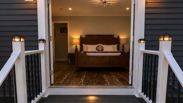 A staircase leading to a bedroom with a bed, a nightstand, and a wall-mounted light fixture. - Lefty’s Poolside Retreat (Lewes)