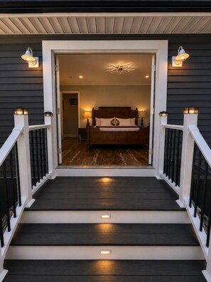 A staircase leading to a bedroom with a bed, a nightstand, and a wall-mounted light fixture. - Lefty’s Poolside Retreat (Lewes)