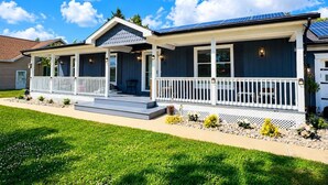 A two-story house with a covered porch, solar panels, and a well-maintained lawn. - Lefty’s Poolside Retreat (Lewes)