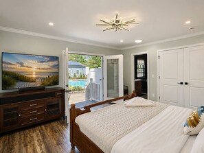 Quarto com cama, televisão, armário de madeira e vista para uma piscina.