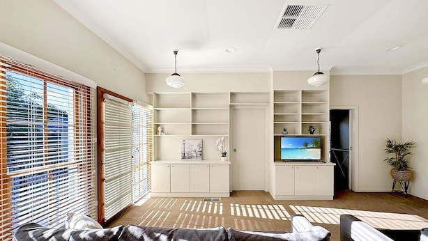 A living room with a sofa, TV, and built-in shelving. - Gurwood Stay - All of the Comforts (Wagga Wagga)